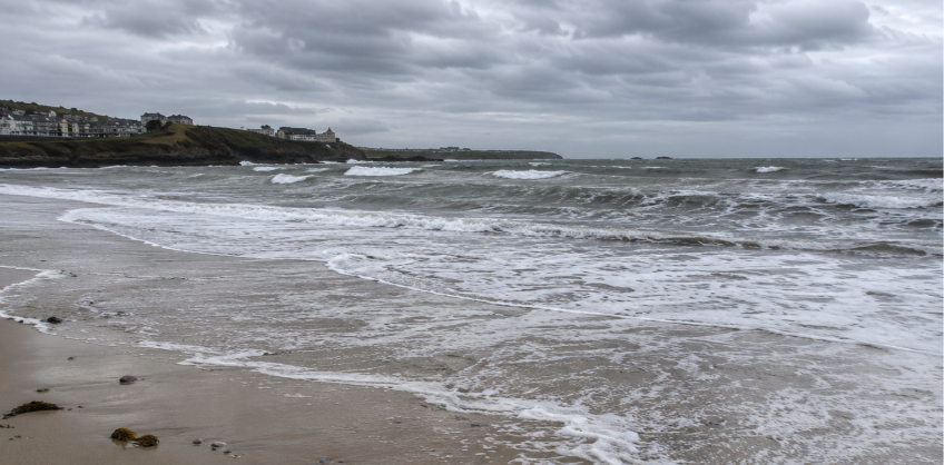 Playa de arena en la costa inglesa con la marea alta bajo un cielo nublado