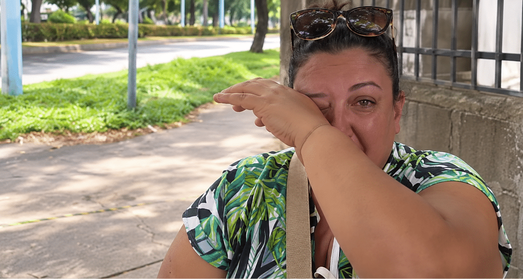 Vendedora cubana emocionada en la calle tras recibir la ayuda de un nicaragüense que le compró toda la mercancía.